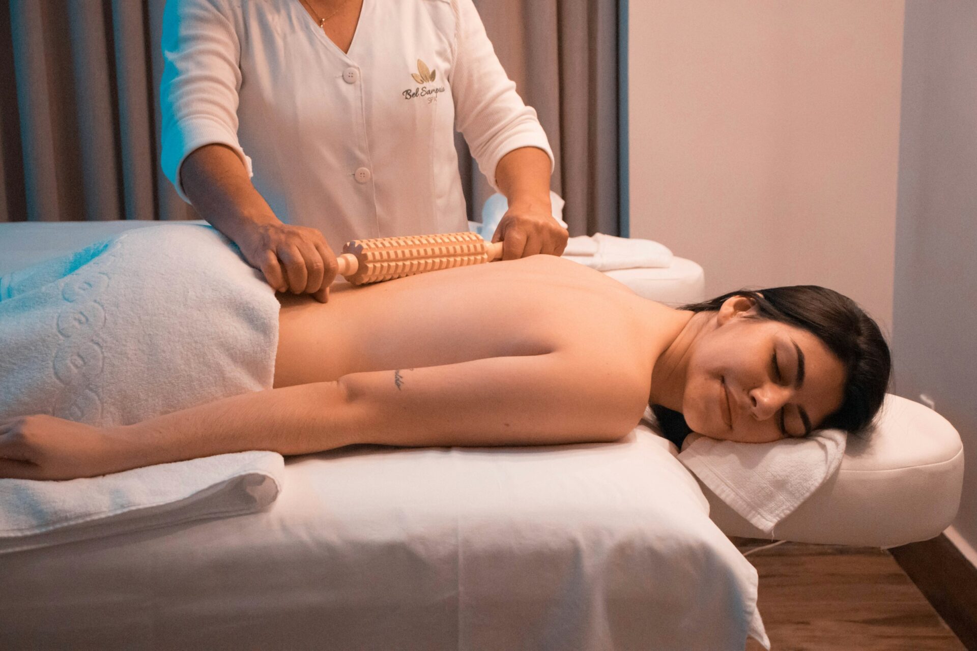 A woman lying on a massage table receiving a roller massage for muscle recovery and flexibility.